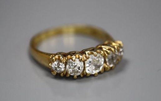 An 18k yellow metal and graduated five stone diamond set half hoop ring, size O, gross 3.8 grams,